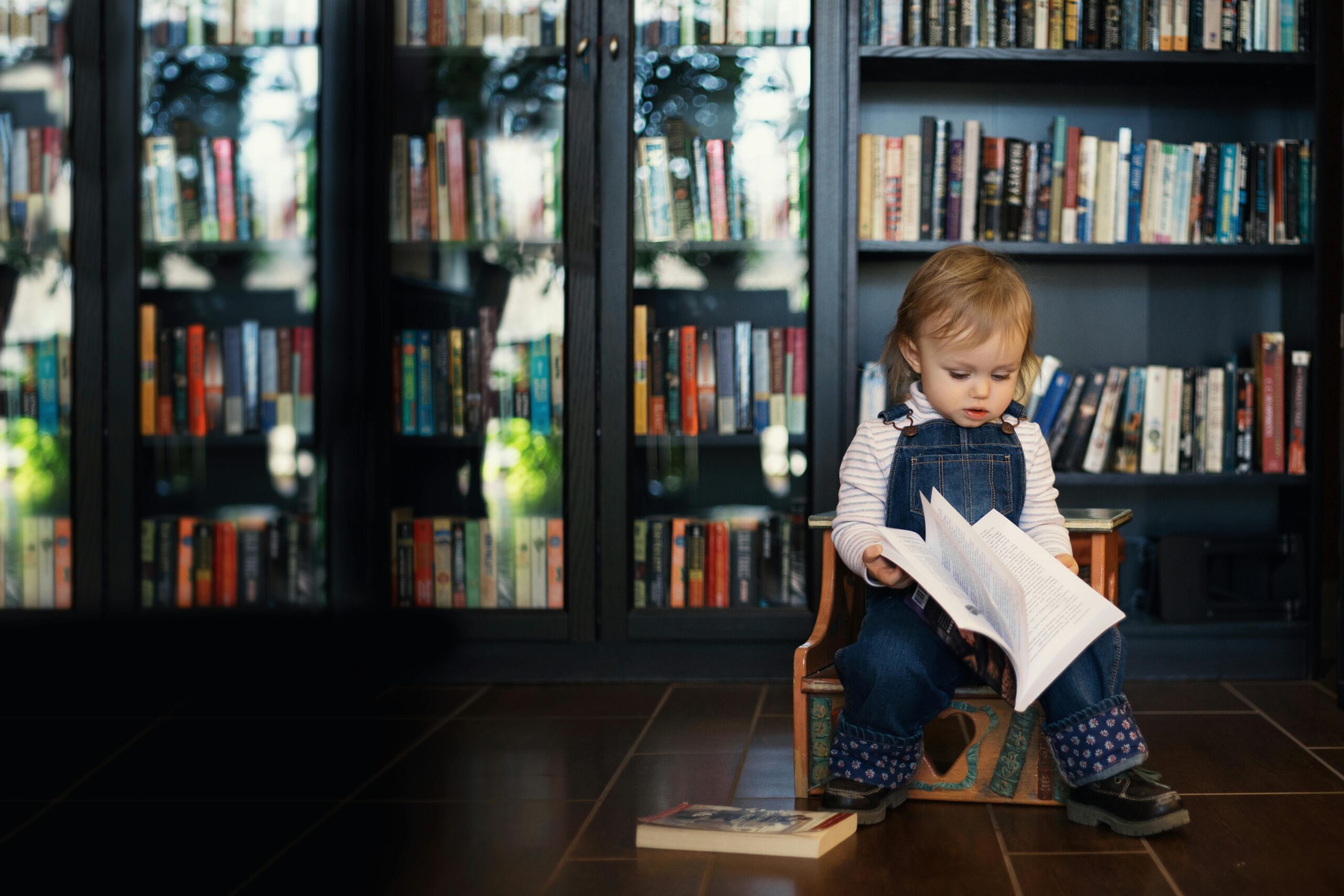 Toddler sitting on a Wooden Chair holding a Book